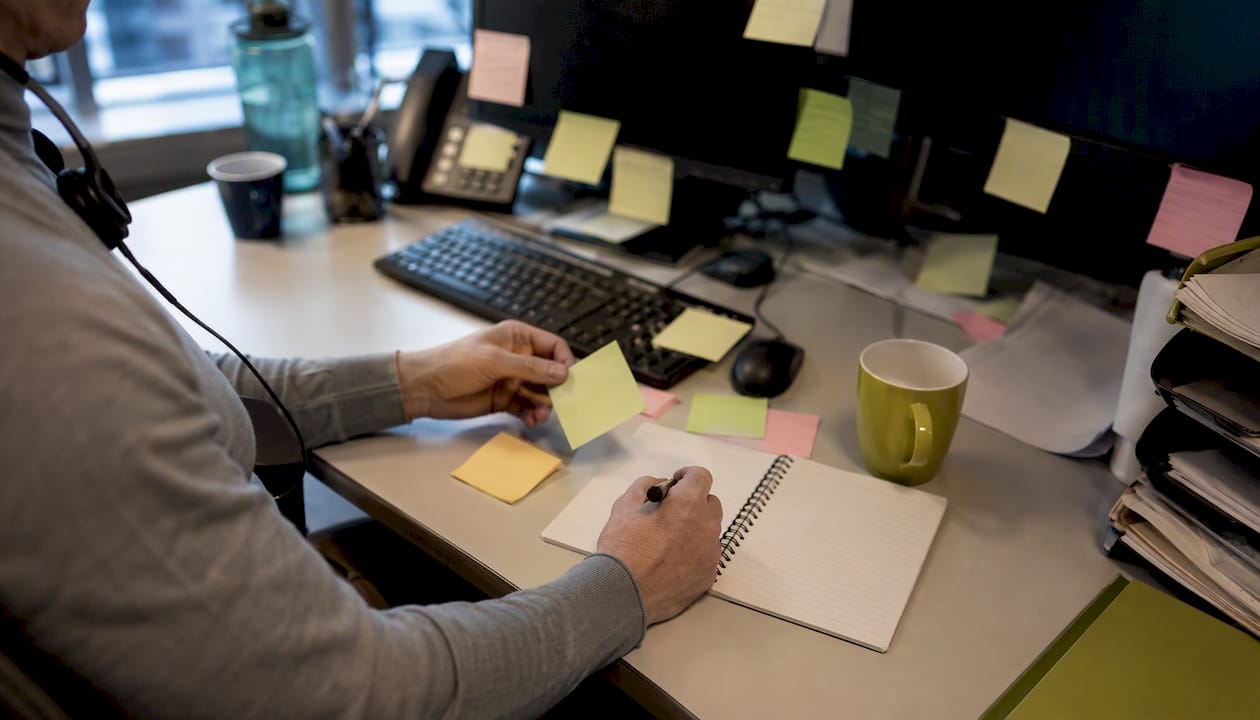 Flera händer i full fart bland papper och prylar på ett stökigt kontor